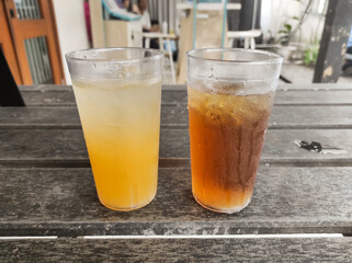 A glass of iced orange and iced tea on a wooden table. A refreshing drink to quench your thirst and accompany spicy food in a restaurant. Drink or beverages photography with negative space