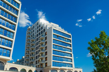 City view on a sunny day. Modern building and houses against the blue sky.
