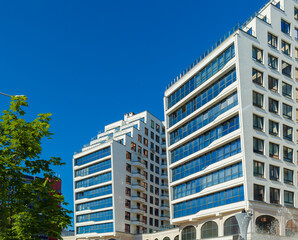 City view on a sunny day. Modern building and houses against the blue sky.