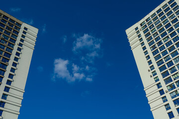 City view on a sunny day. Modern building and houses against the blue sky.