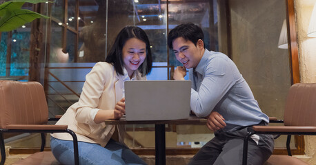 Couple engaged in collaborative work while reviewing content on a laptop in a cozy cafe in Hanoi, Vietnam