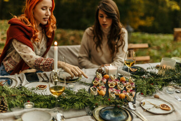 Women enjoying festive outdoor meal with appetizers and wine