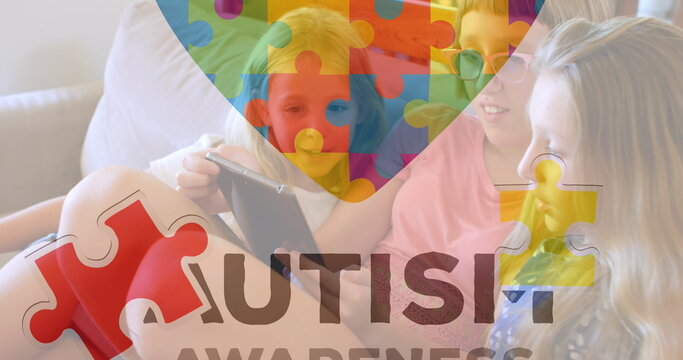 Sharing three preteen girls examining tablet on living room sofa, with autism awareness puzzle - Powered by Adobe