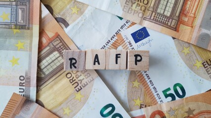 RAFP acronym made of wooden letter cubes on pile of Euro banknotes. Retraite Additionnelle de la Fonction Publique (Additional Pension for Public Servants)