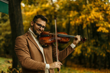 Musician playing viola in autumn park enjoying classical music
