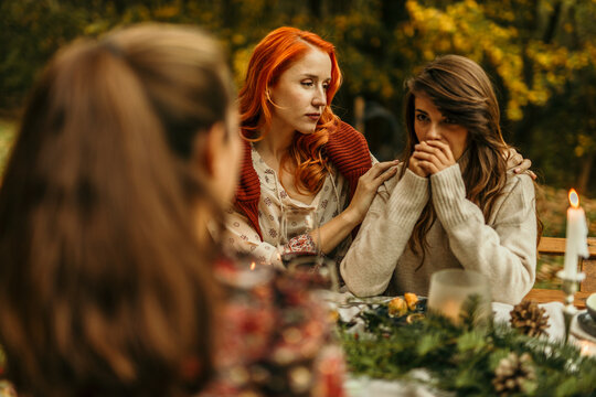 Woman comforting her sad friend during a christmas dinner in the woods
