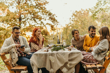 Friends enjoying thanksgiving dinner outdoors in beautiful autumn setting