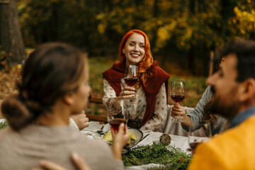 Friends raising glasses of wine at outdoor autumn feast