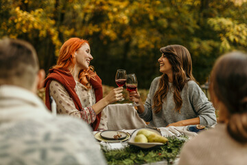Friends enjoying wine at an autumn outdoor dinner party