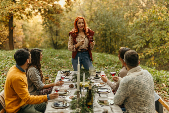 Woman giving a toast to friends at an autumn outdoor dinner party