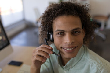 Headset with microphone is resting on desk alongside keyboard and smartphone near window