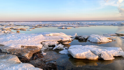 Beautiful winter landscape of a frozen sea coast at sunset