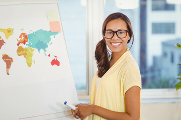 African American woman presenting world map on flip-chart easel in meeting room holding marker