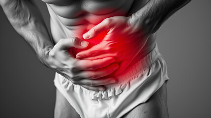 A black and white close-up of a man wearing white underwear, clutching his groin in pain. A red glow highlights discomfort, symbolizing a medical issue such as pelvic pain or prostate problems.