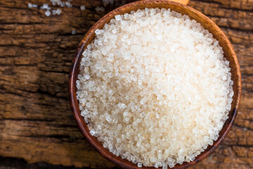 white sugar in wooden bowl, wooden scoop on old wooden background
