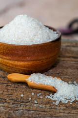 white sugar in wooden bowl, wooden scoop on old wooden background