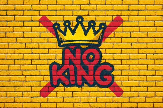 A vibrant mural on a yellow brick wall displays the slogan 'NO KING' with a crossed crown symbol. The artwork reflects protest sentiments against political policies.