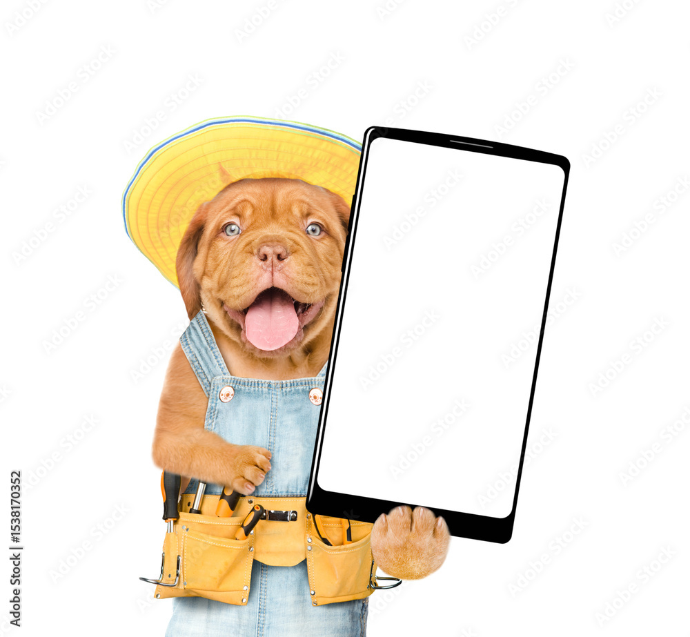 Poster happy mastiff puppy wearing yellow hat, overalls with tool belt showing big smartphone with white bl