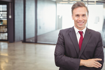Businessman standing near glass-walled meeting room in corporate office, with bookshelf binders