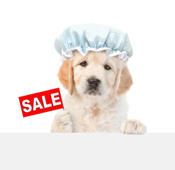 Cute golden retriever puppy wearing shower cap shows signboard with labeled "sale" above blank white banner. isolated on white background