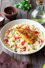 Orzo pasta with fried chicken breast, tomatoes and herbs. Italian food.