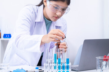 Teen scientist girl conducting science test by carefully evaluating blue solution in laboratory....