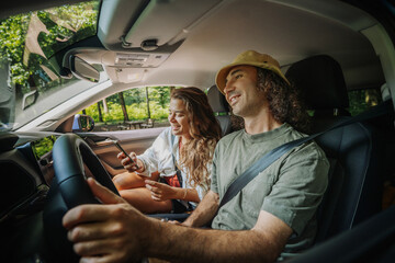 Happy young couple driving a car to the countryside..Summer vacation and travel concept