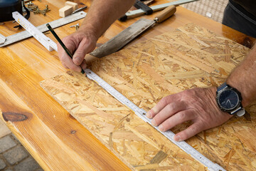 Ein Heimwerker beim Anzeichen mit Zollstock und Bleistift, Hobby Holzbau 