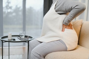 Senior woman suffering from back pain at home