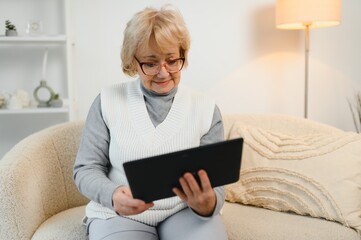 Old happy woman having a video call with her family on a tablet