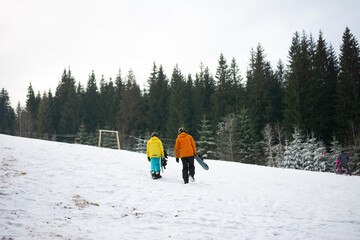 Enjoying a winter adventure together on a snowy slope while heading for some fun snowboarding near...