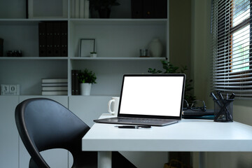 Modern workspace with blank screen laptop, coffee mug, and office supplies