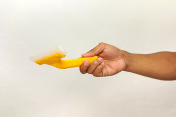 Hand holding a yellow and white squeegee against a white background, cleaning tool
