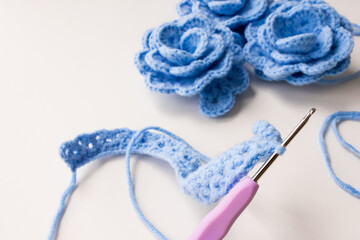 Handmade blue crochet flowers with hook and yarn on white background