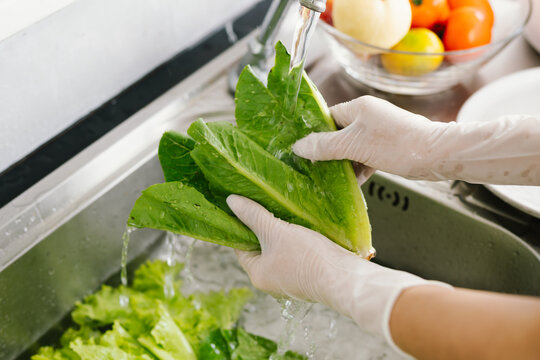 Woman washing fresh vegetables at kitchen sink, practicing hygiene and food safety indoors to prevent illness during pandemic, ensuring healthy lifestyle and cleanliness.