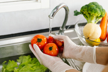 Woman washing fresh vegetables at kitchen sink, practicing hygiene and food safety indoors to prevent illness during pandemic, ensuring healthy lifestyle and cleanliness.