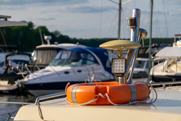 Lifebuoy and spotlight on the deck of a yacht, with moored motorboats in the background. A summer...
