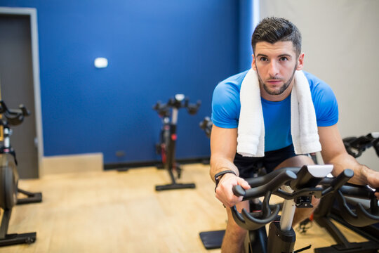 Fototapeta Spin bikes lining up against bright blue wall and resting on light wood floor near doorway