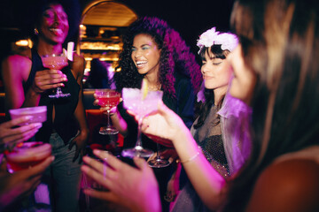 Young women enjoying a bachelorette party celebration with cocktails and laughter