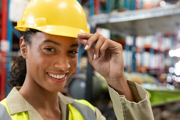 Worker wearing yellow hard hat and hi-vis vest in warehouse with racks and boxes