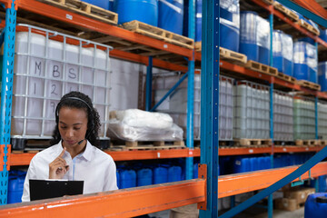 Warehouse employee holding clipboard and pen and inspecting inventory in warehouse with MBS12 drums