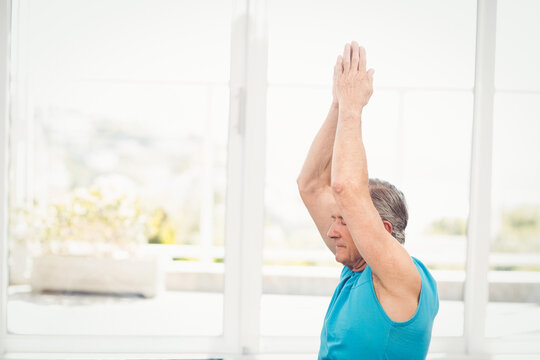 Fototapeta man performing yoga stretch in yoga studio by tall windows, with planter outside