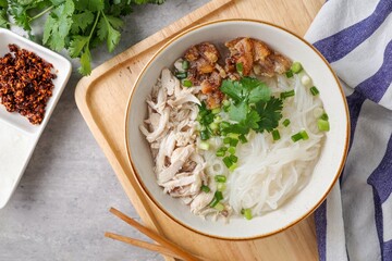 Clear chicken noodle soup with thin rice noodles in ceramic bowl with chopsticks
