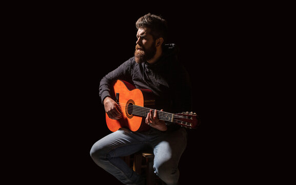 Bearded guitarist plays. Beard hipster man sitting. Music concept. Man's hands playing acoustic guitar, close up. Music festival. Male musician playing guitar, music instrument