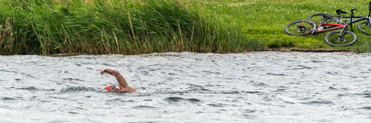 Ein Sportler schwimmt in einem See bei leichtem Wellengang