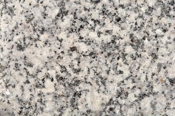A close-up of a light gray granite texture with dark specks