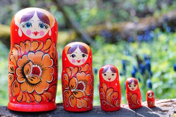 Wooden nesting dolls stand in a row in the forest.