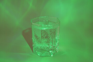 A glass of water on a green background.