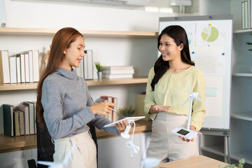 ESG Focus. Two women presenting renewable energy solutions in a collaborative office environment.