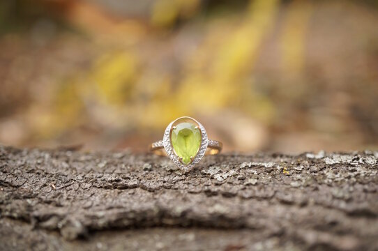 A precious ring with chrysolite on a wooden background.